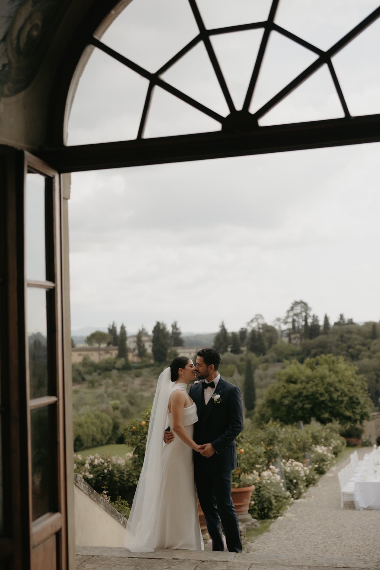 Novios asomados a un ventanal con el campo al fondo